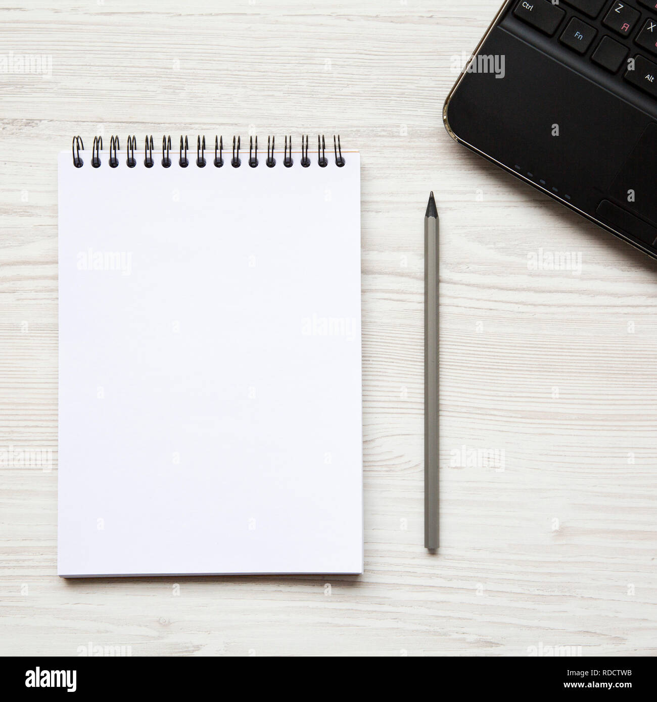 Workspace with laptop, notepad and pencil on white wooden table ...