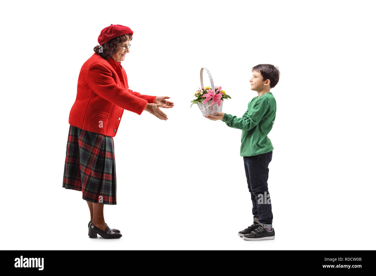 Full length shot of a young boy giving a basket with flowers to his grandmother isolated on white background Stock Photo