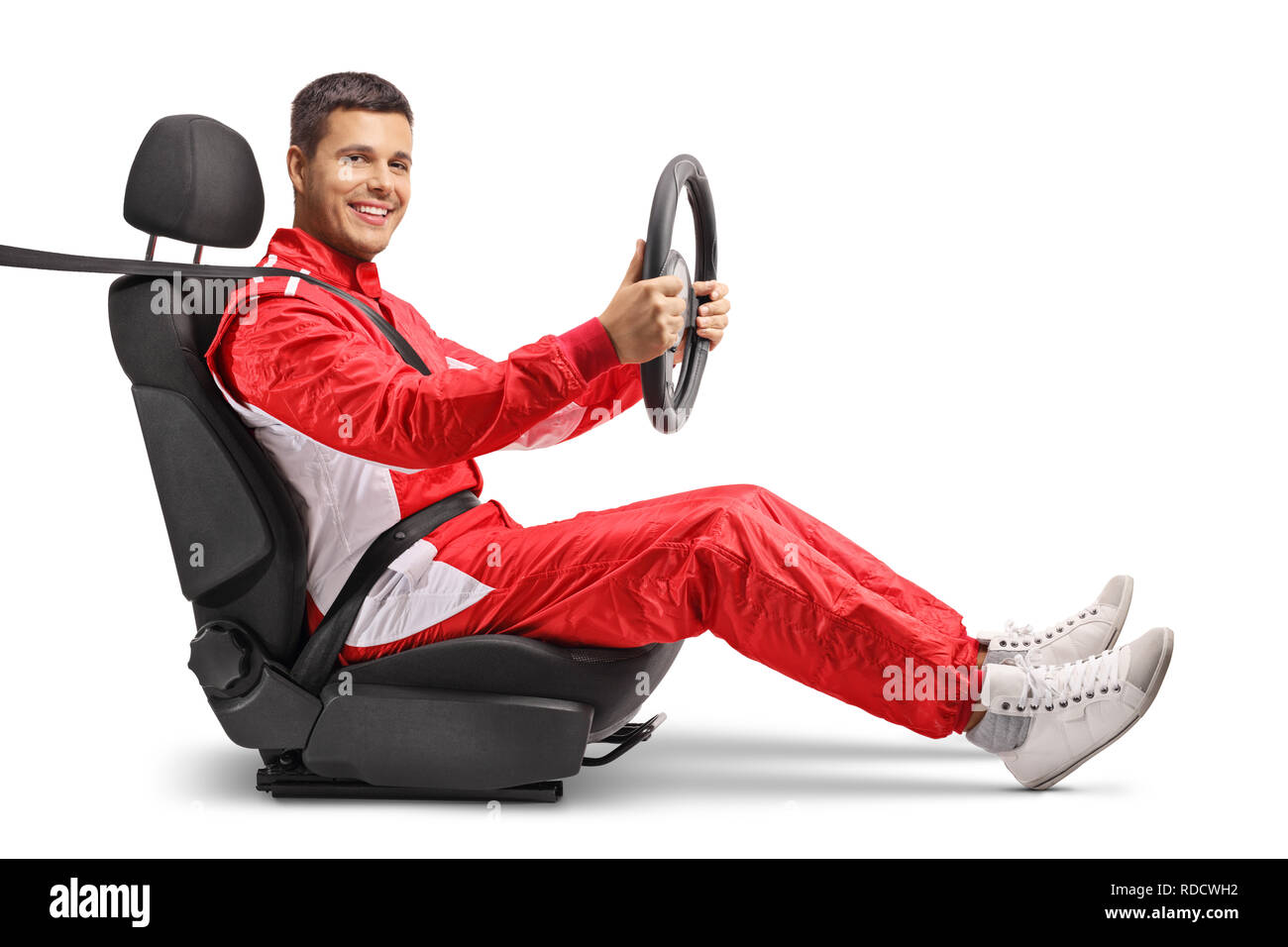 Full length shot of a male racer in a car seat holding a steering wheel and smiling at the camera isolated on white background Stock Photo
