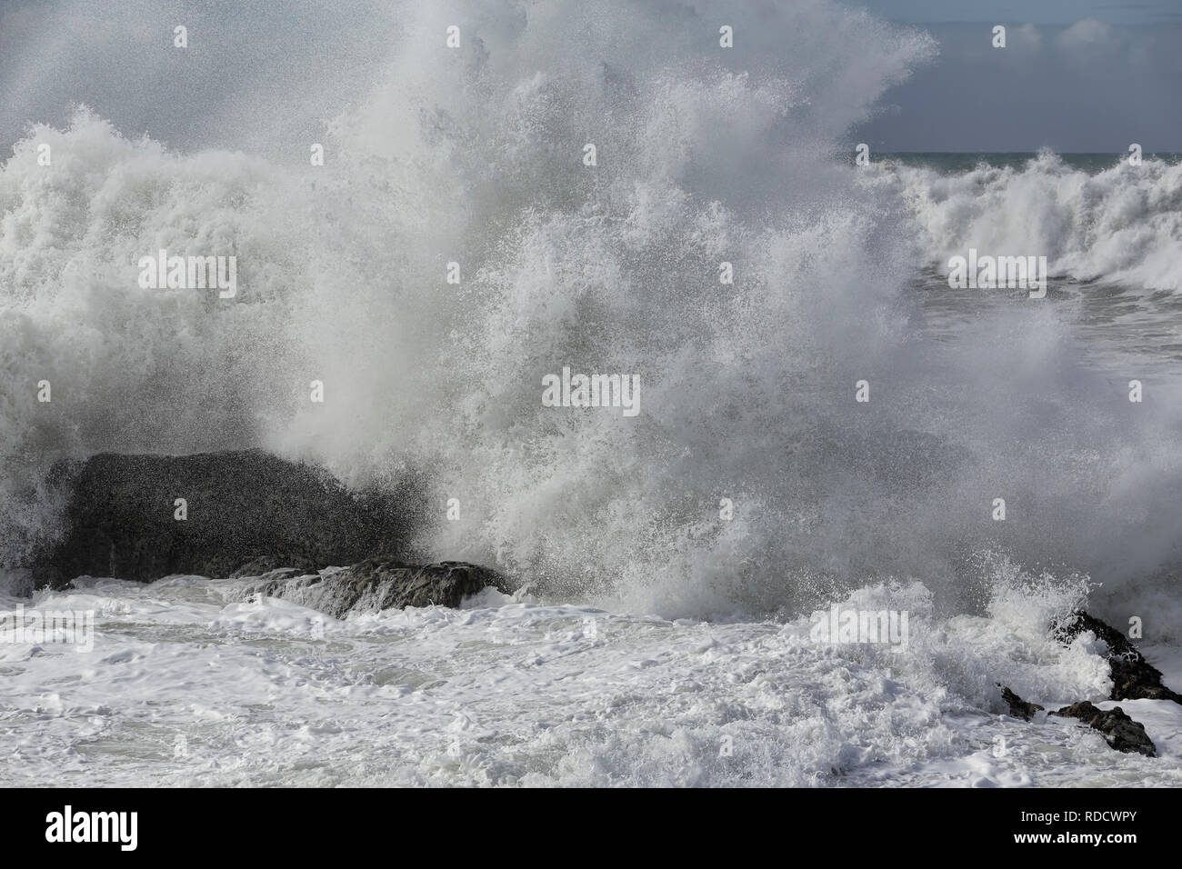 Big splash from waves breaking against beach rocks Stock Photo - Alamy