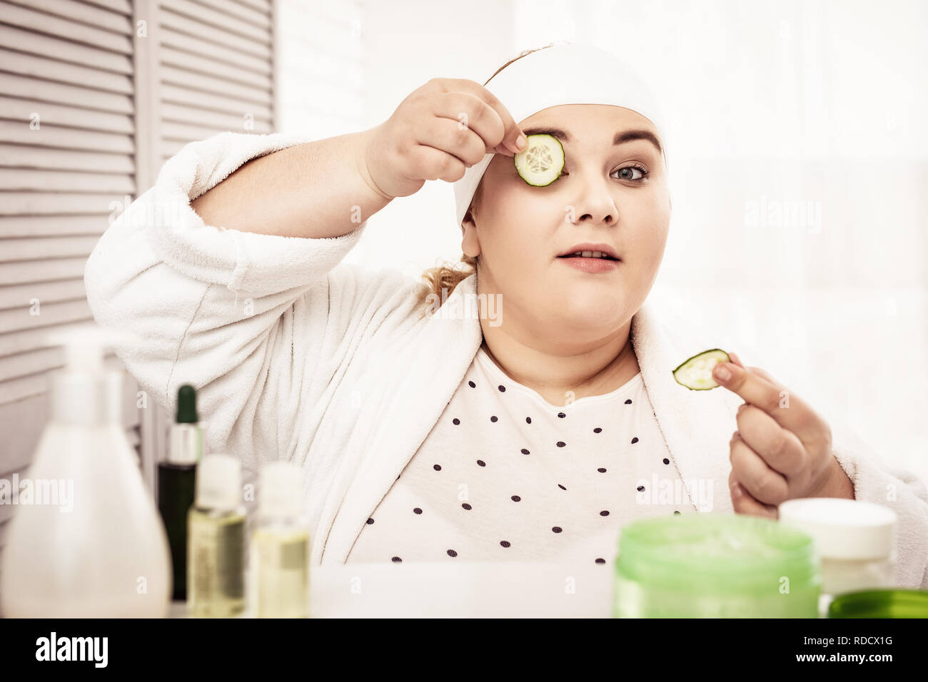 Focused big woman putting cucumbers on her eyelids Stock Photo Alamy
