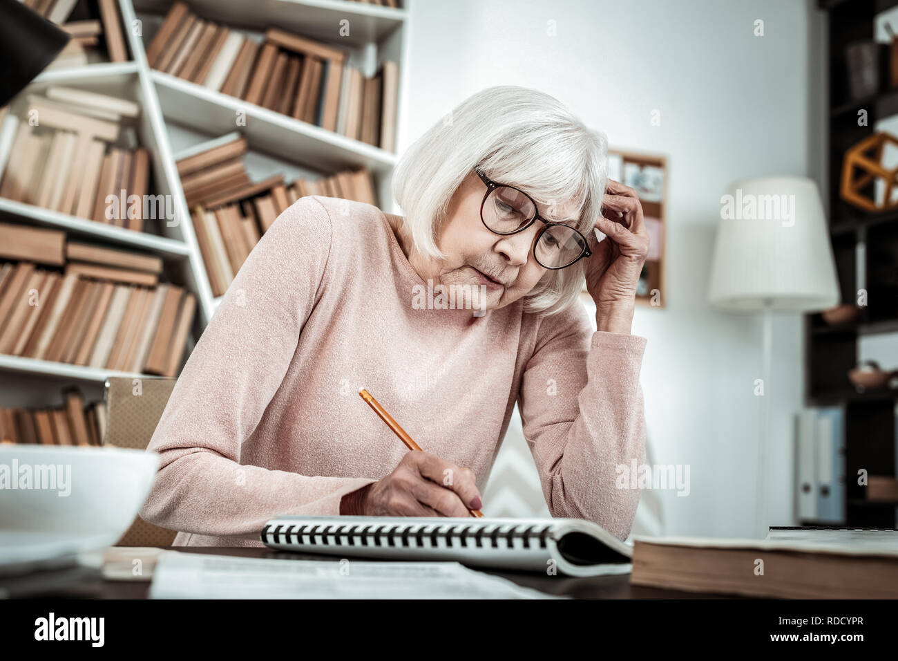 Concentrated senior female preparing task for lesson Stock Photo - Alamy