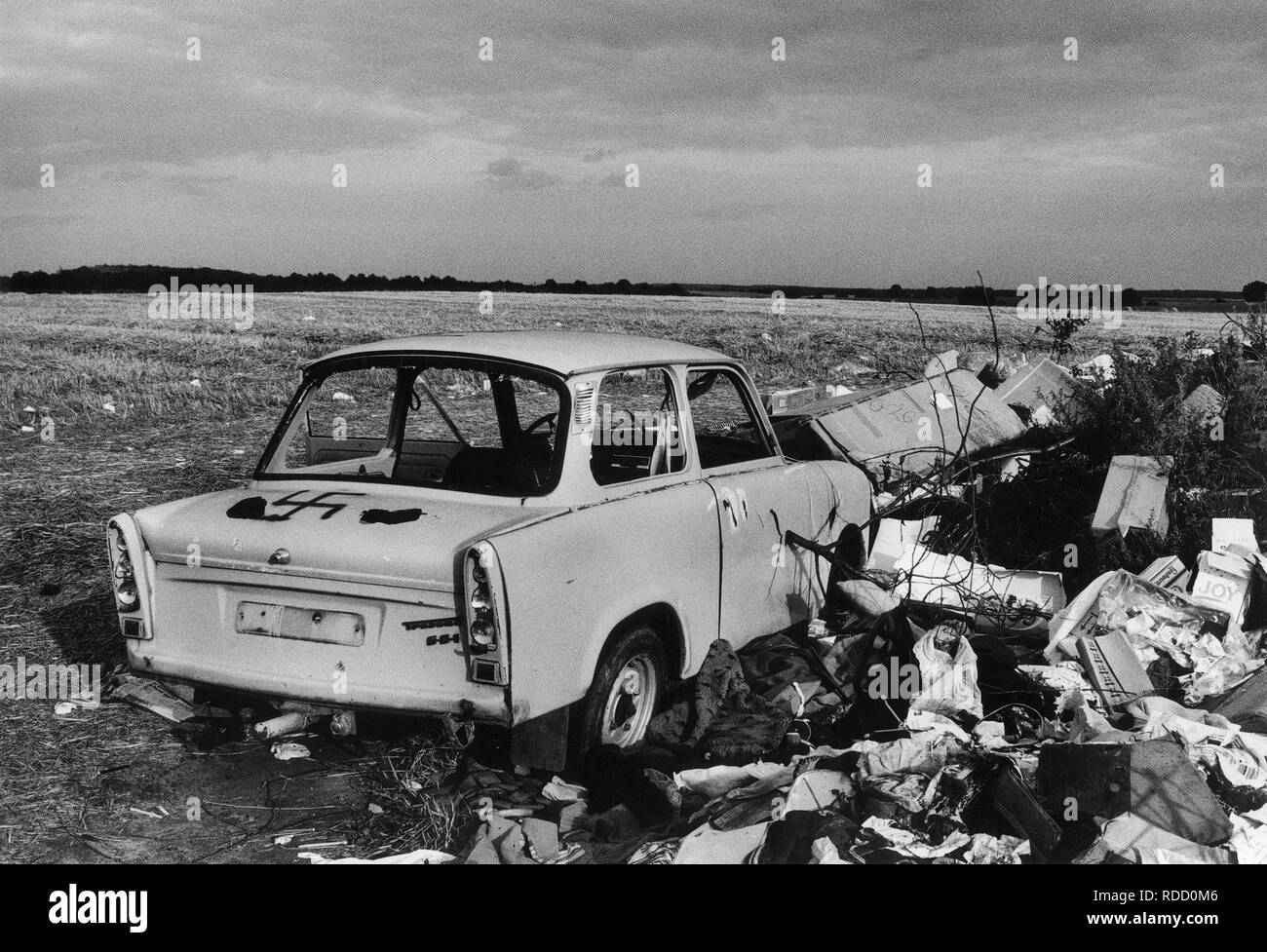 GERMANY in 1990 after reunification, former East Germany, German Democratic Republic GDR, typical plastic car Trabant also called Trabbi with fascist Nazi symbol swastika Hakenkreuz on wild dumping site in village Plauerhagen, Mecklenburg, people have dumped their East German car in exchange to new western cars, scan from black and white negative with film grain Stock Photo