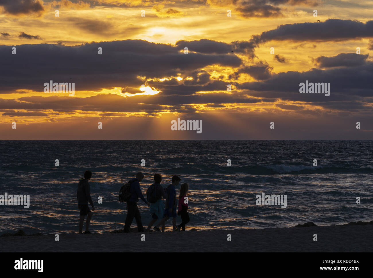 25 December 2019 - South Beach Miami, Florida, USA. Holidaymakers walking on the beach and enjoying colourful sunrise. Stock Photo