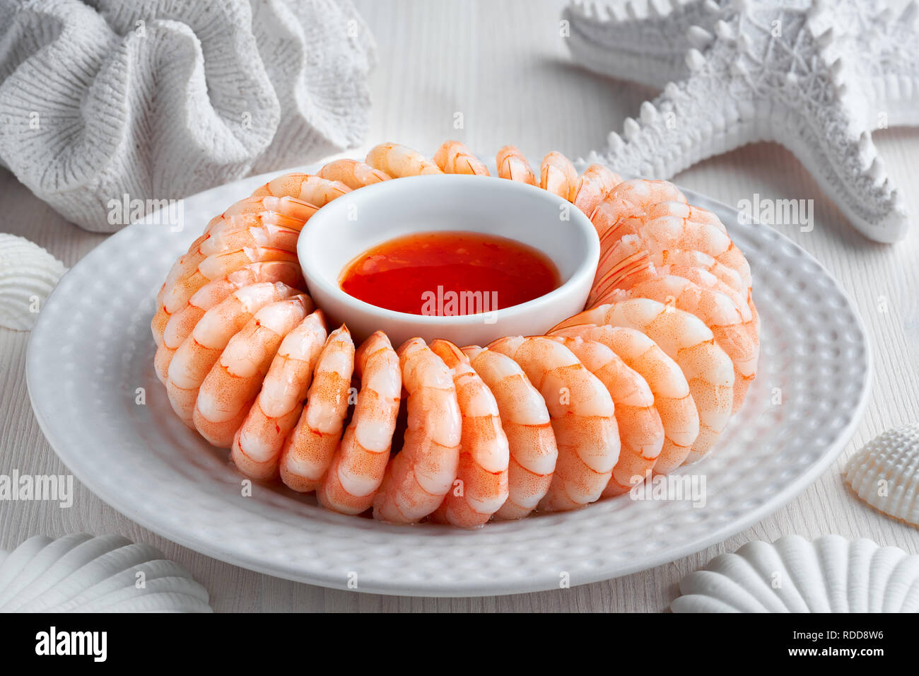 Close-up on shrimp ring with sause on light background with white sea decorations Stock Photo