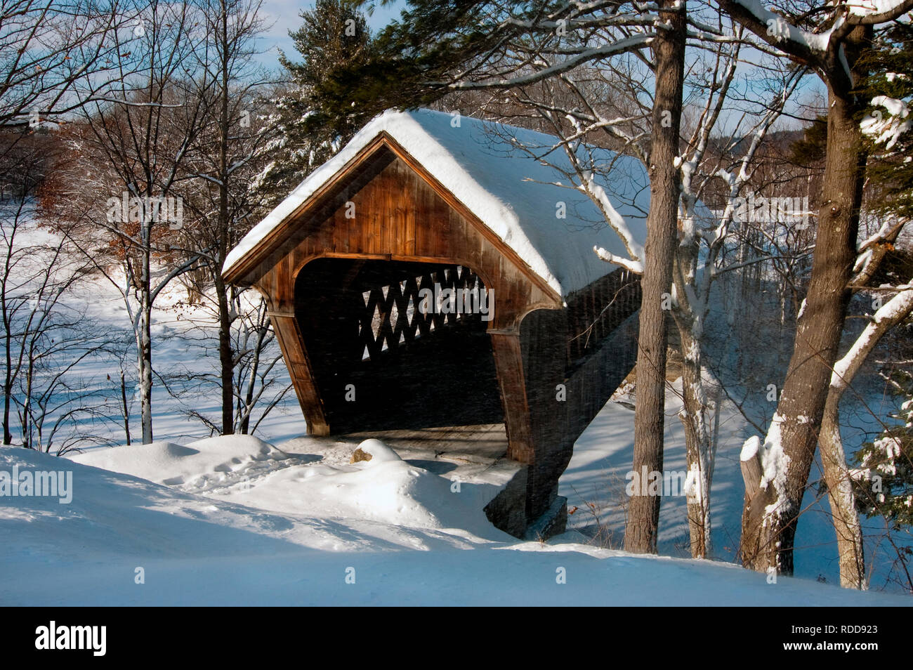 Wind blows snow around Henniker covered bridge in New Hampshire Stock