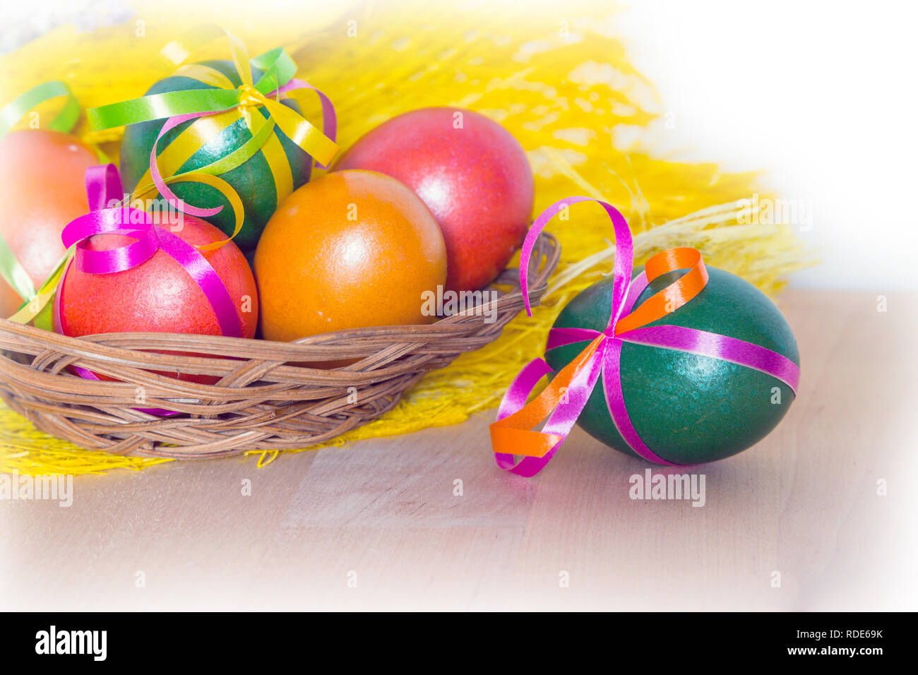 Brightly colored bow decorated easter eggs in basket, holiday background Stock Photo