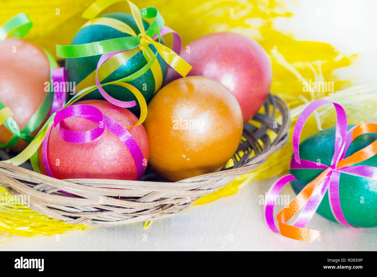 Brightly colored bow decorated easter eggs in basket, holiday background Stock Photo