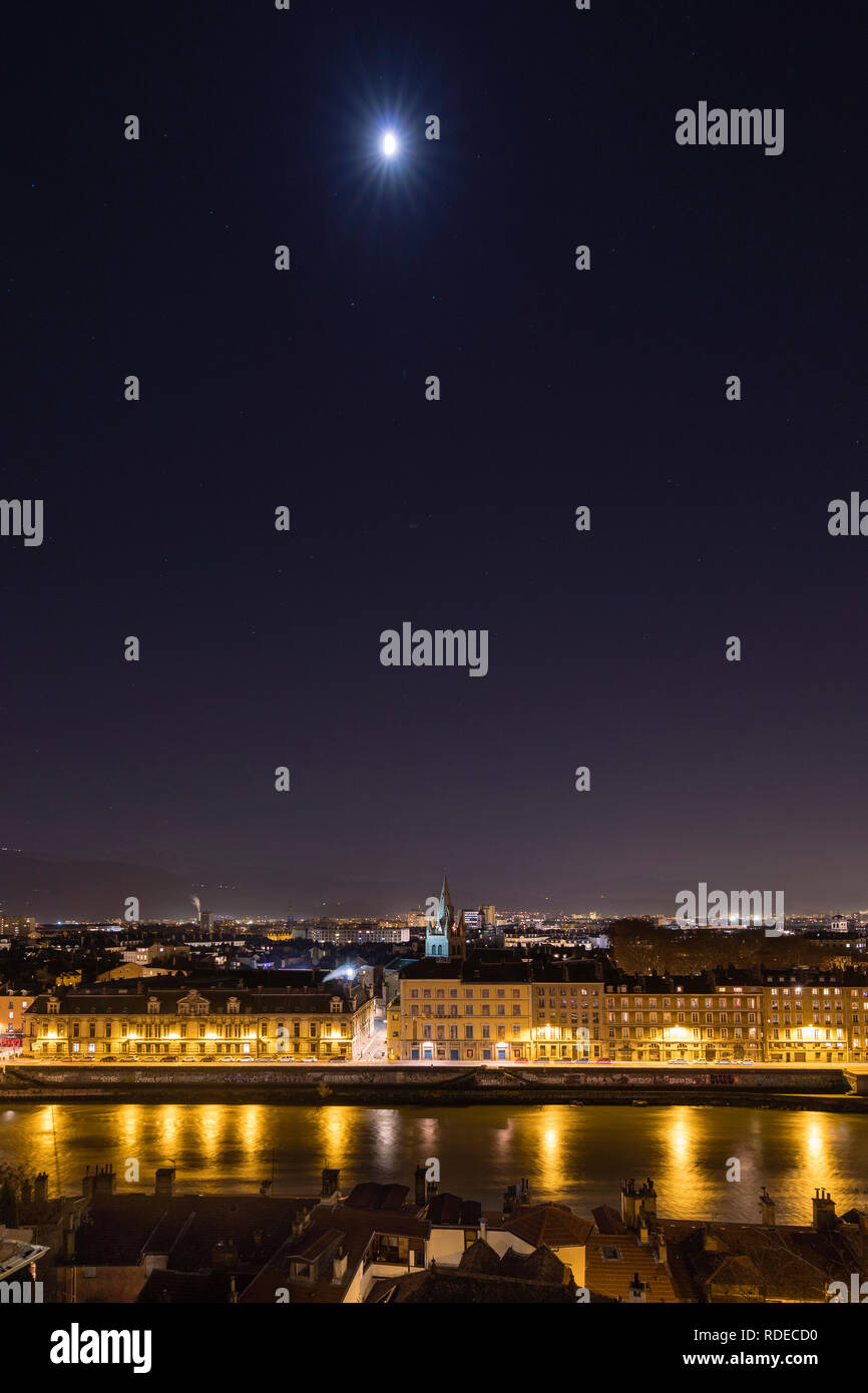 Grenoble, France, January 2019 : City at night with isere river, the moon and stars in the sky. Stock Photo