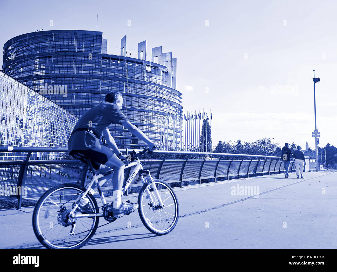 STRASBOURG, FRANCE - AUG 20, 2016: Blue color toned chromacity of senior cyclist sport workout in front of the european parliament building in Strasbourg on a calm summer day Stock Photo