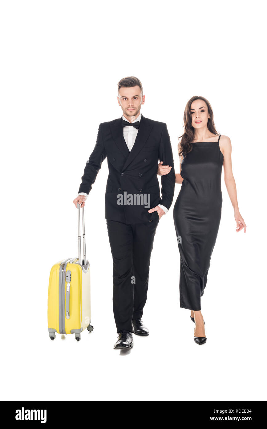 beautiful elegant couple in black clothes walking with travel bags, isolated on white Stock Photo