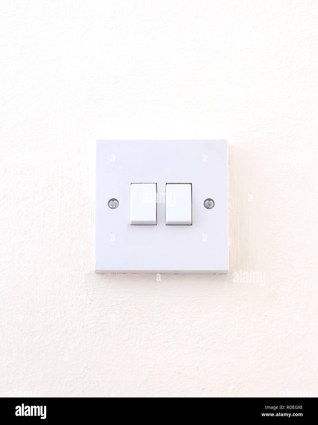A white light switch on a plain wall Stock Photo Alamy