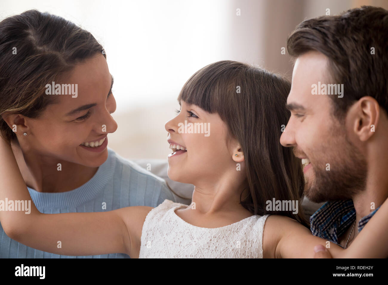 Cute daughter looking at dad laughing having fun with parents Stock Photo