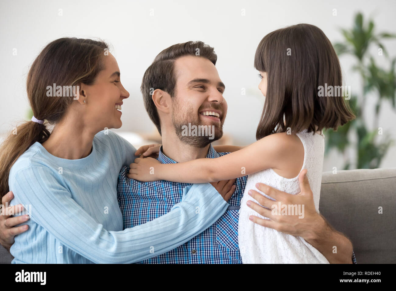 Cute kid daughter and wife embracing happy dad having fun Stock Photo