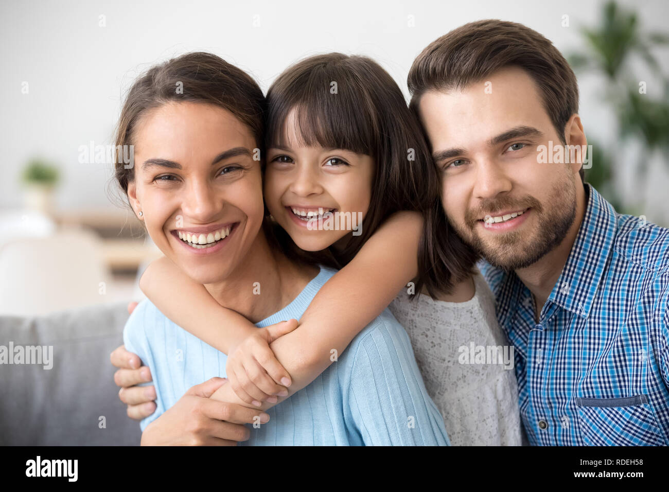 Cheerful beautiful family of three embracing laughing looking at Stock Photo