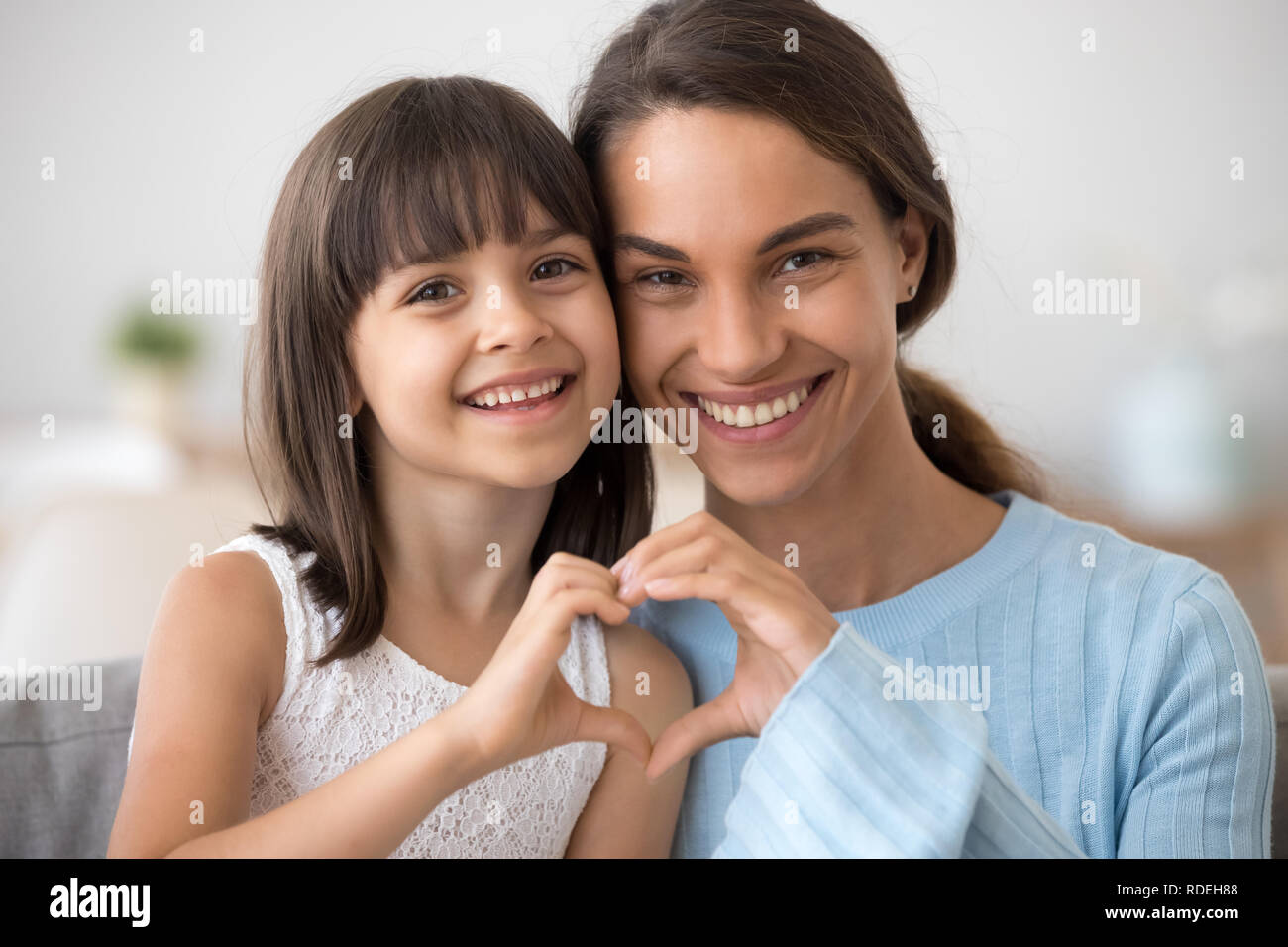 Cute daughter and happy mother join hands in heart shape Stock Photo
