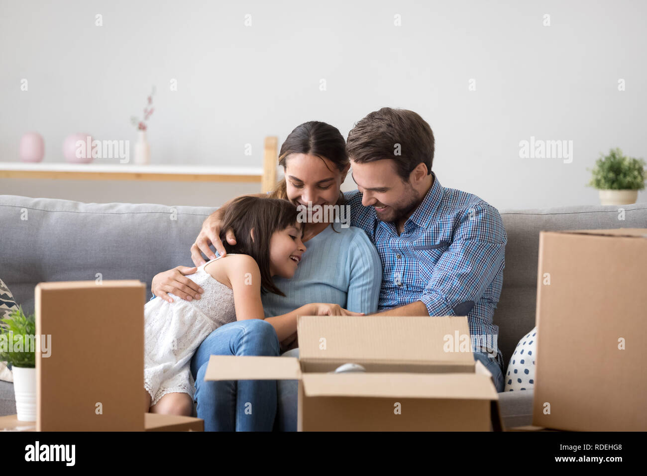 Happy parents with kid embracing on sofa enjoy moving day Stock Photo