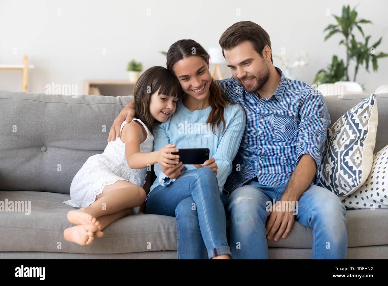Smiling mother holding smartphone taking family selfie or watchi Stock Photo