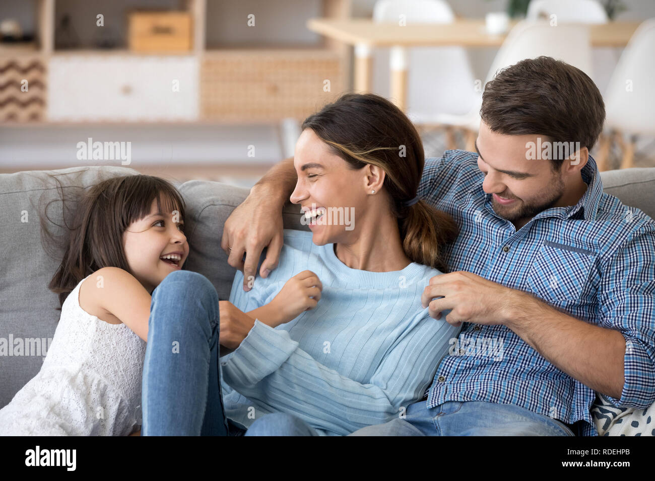 Kid daughter and dad tickling mom having fun playing together Stock Photo