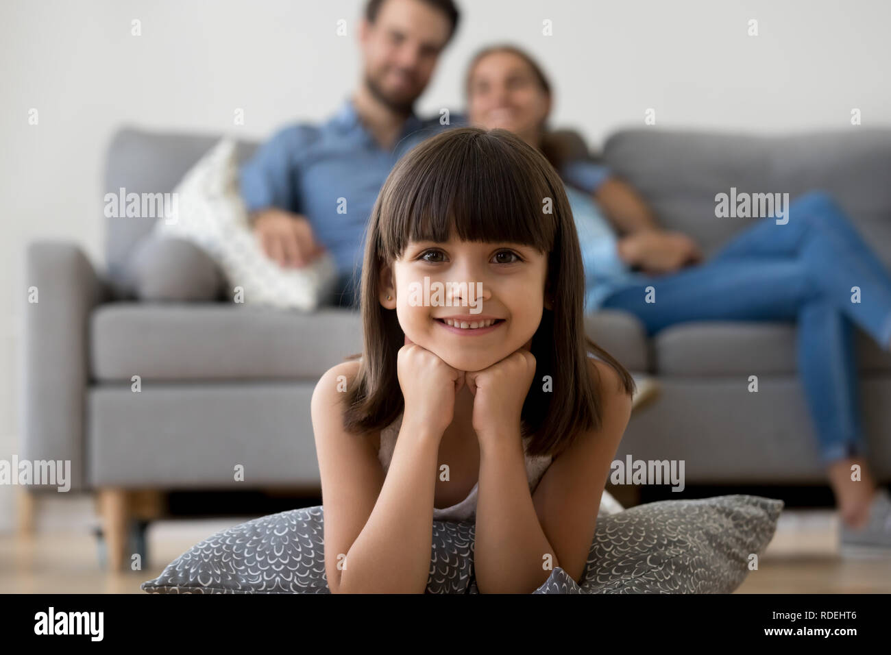 Adorable little girl looking at camera lying on warm floor Stock Photo