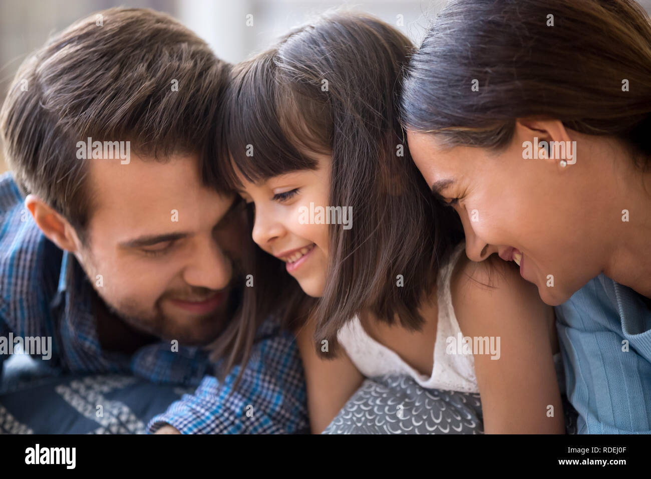 Affectionate family parents and cute child daughter bonding tend Stock Photo