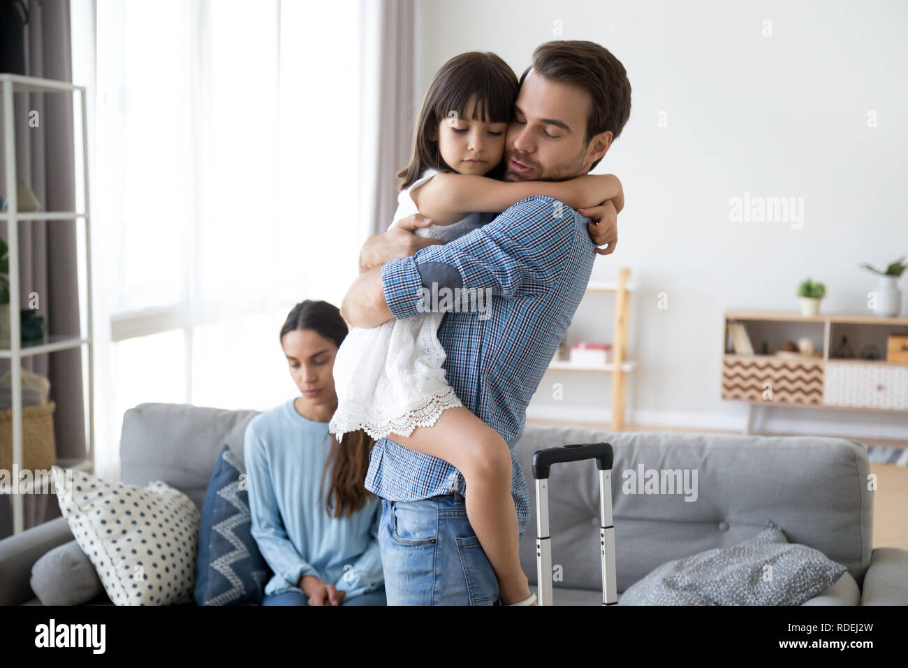 Sad little girl upset by father leaving embracing dad Stock Photo