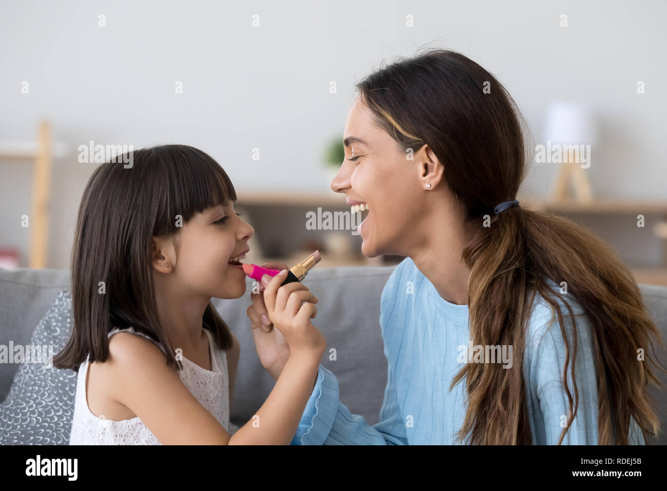 Smiling mom and happy kid daughter doing makeup together  Stock Photo