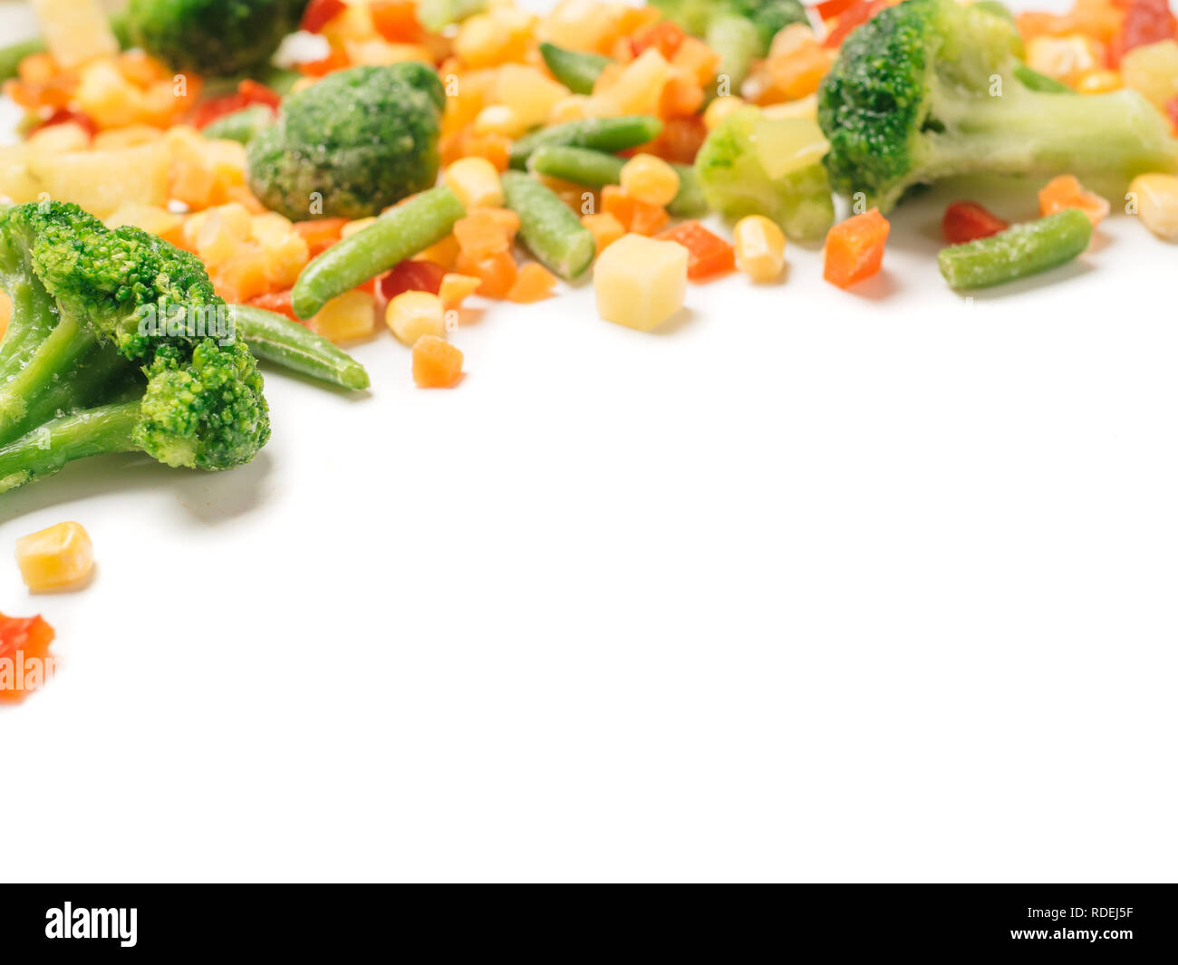 Frozen vegetables assorted isolated on white with clipping path. Frosen vegetables with ice Isolated one edge. Frozen mix vegetables with copy space for text. Stock Photo