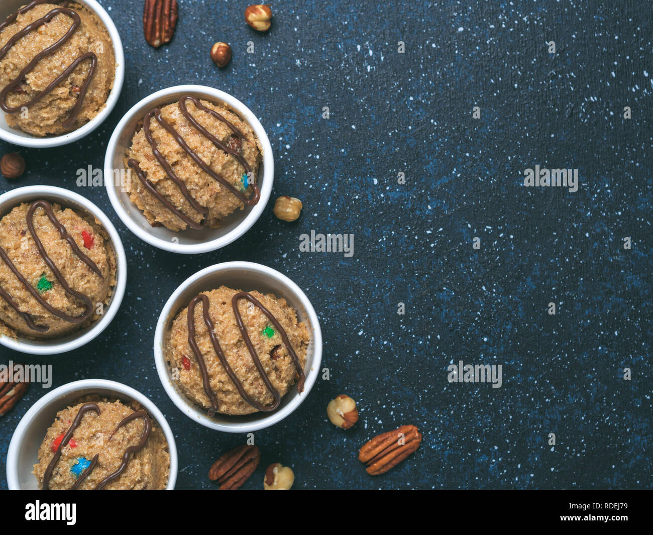 Safe-to-eat raw monster cookie dough in small portion bowl on dark blue background. Ideas and recipes for kids and toddlers meal. Top view or flat-lay. Copy space for text. Stock Photo
