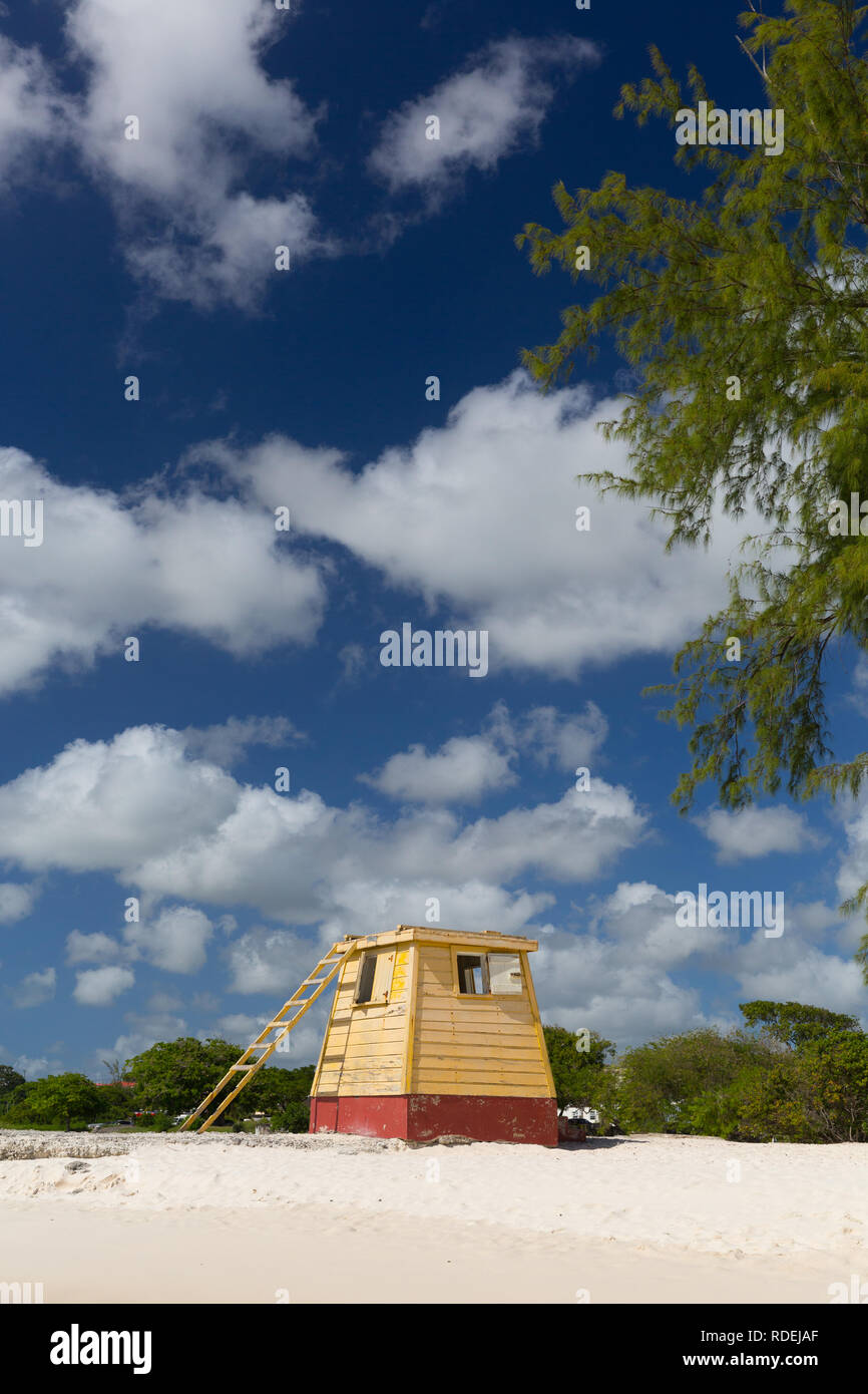 The original yellow wooden lifeguard station on Enterprise Beach, Barbados, bathed in glorious blue skies with puffy clouds. Stock Photo