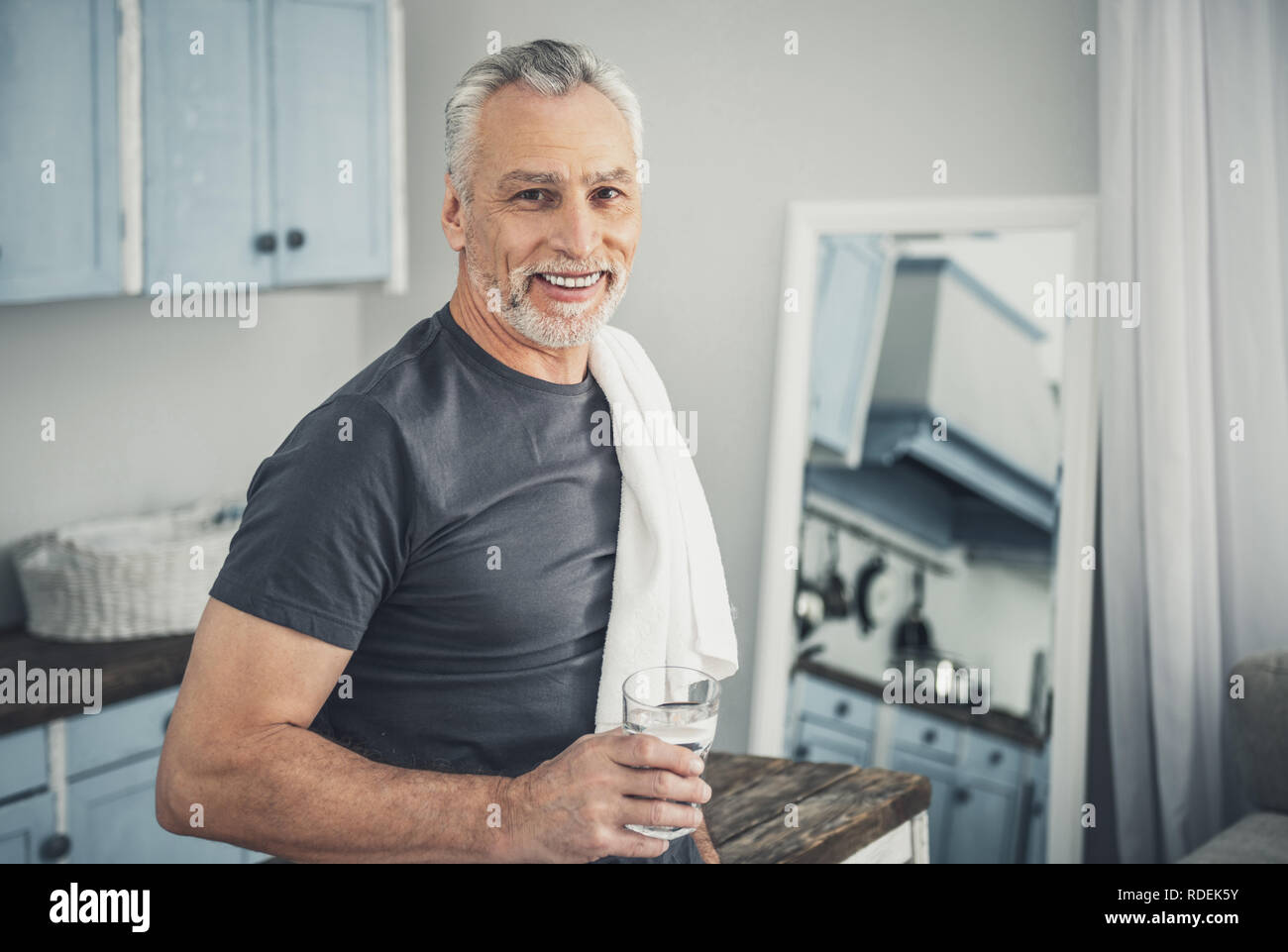 Smiling man drinking glass of water after morning shower Stock Photo