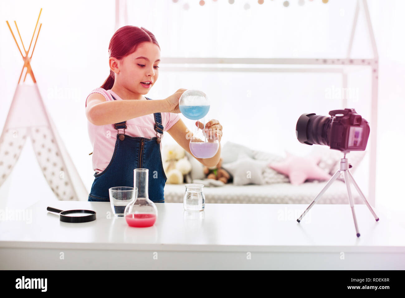 Dark-haired blogger filming video about chemistry in her living room Stock Photo