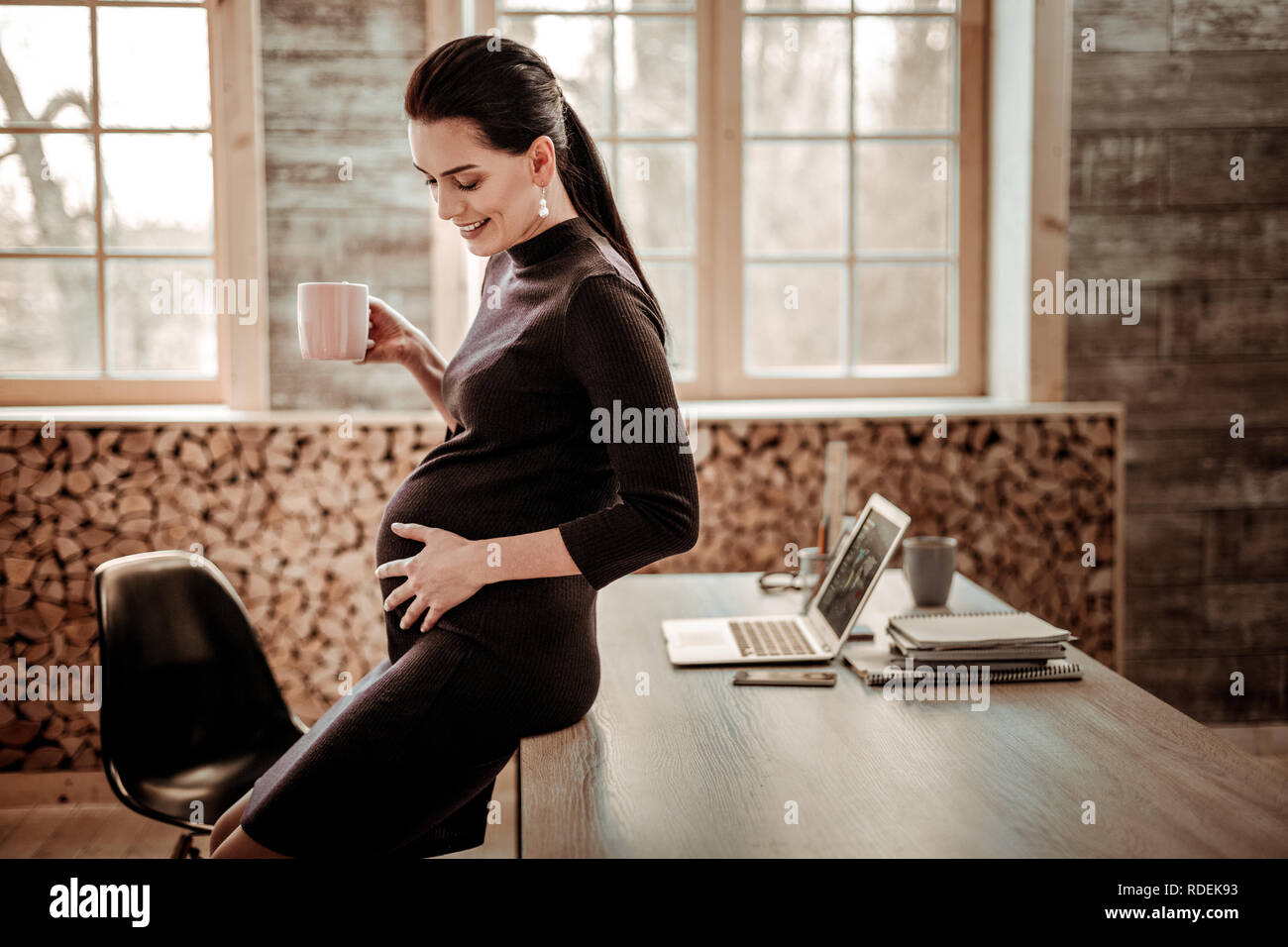 Delighted pregnant woman having a cup of tea Stock Photo - Alamy
