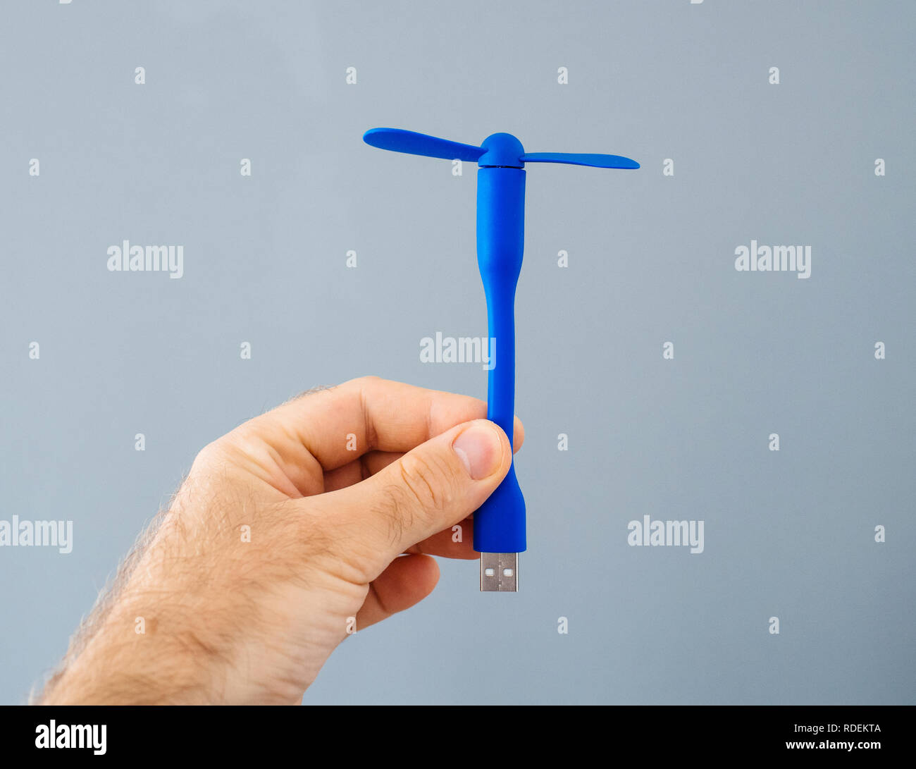 USB fan in male hand against gray background preparing for the hot