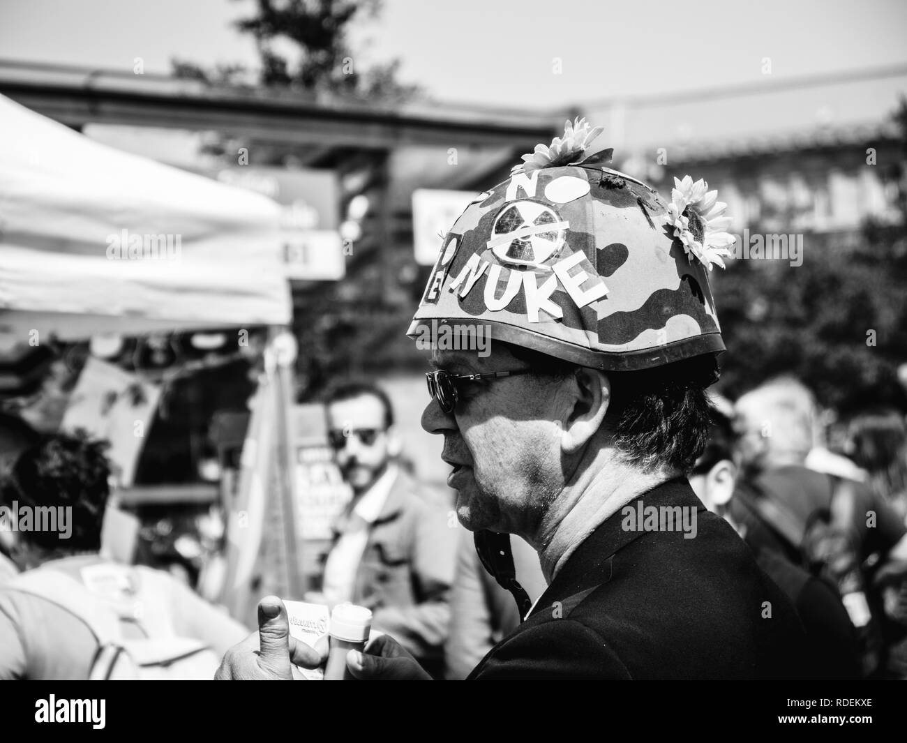STRASBOURG, FRANCE - MAY 5, 2018: People making a party protest Fete a Macron party for Macron - man with military helmet with NO NUKE text and flowers Stock Photo