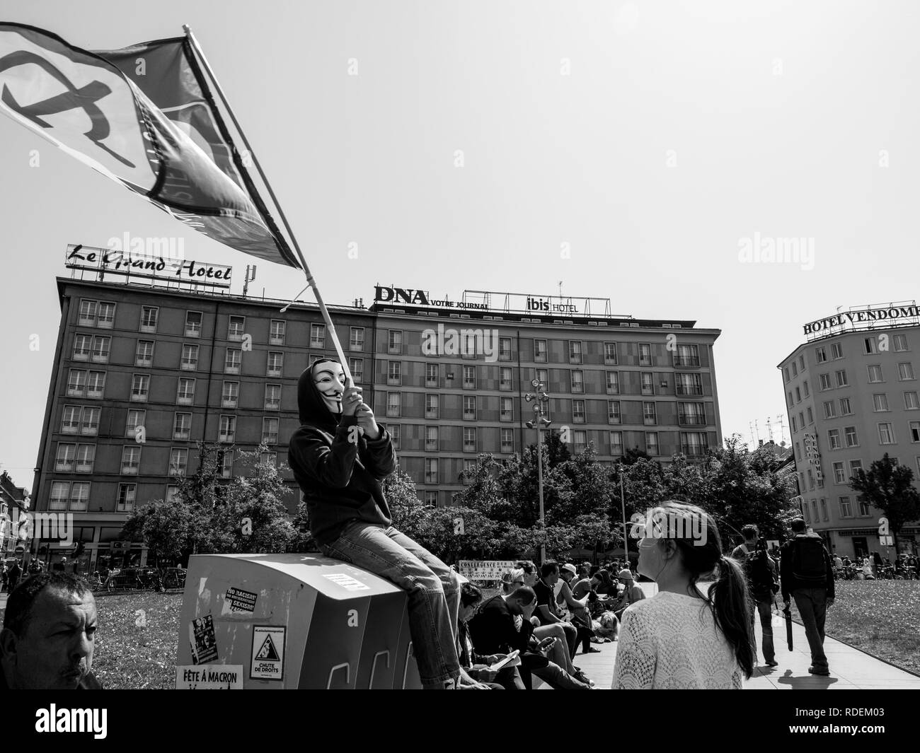 STRASBOURG, FRANCE - MAY 5, 2018: People making a party protest Fete a Macron in front of Gare de Strasbourg - young boy with anonymous mask waving communist flag Stock Photo