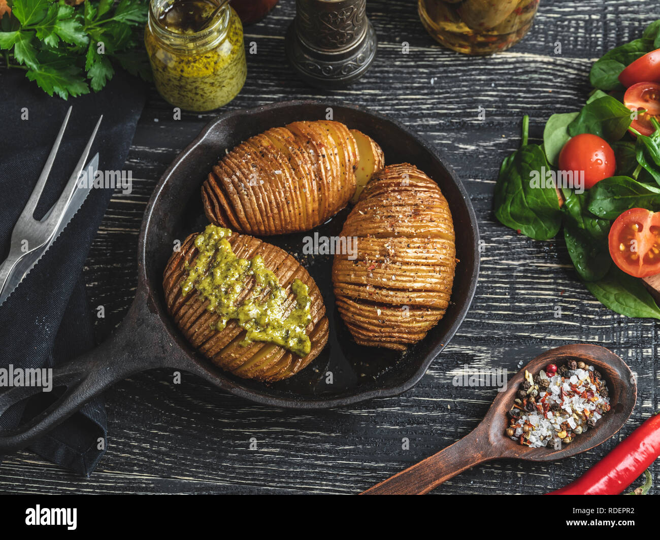 Homemade baked roasted potatoes wholly in skin, salad. Cast iron pan on the table Stock Photo