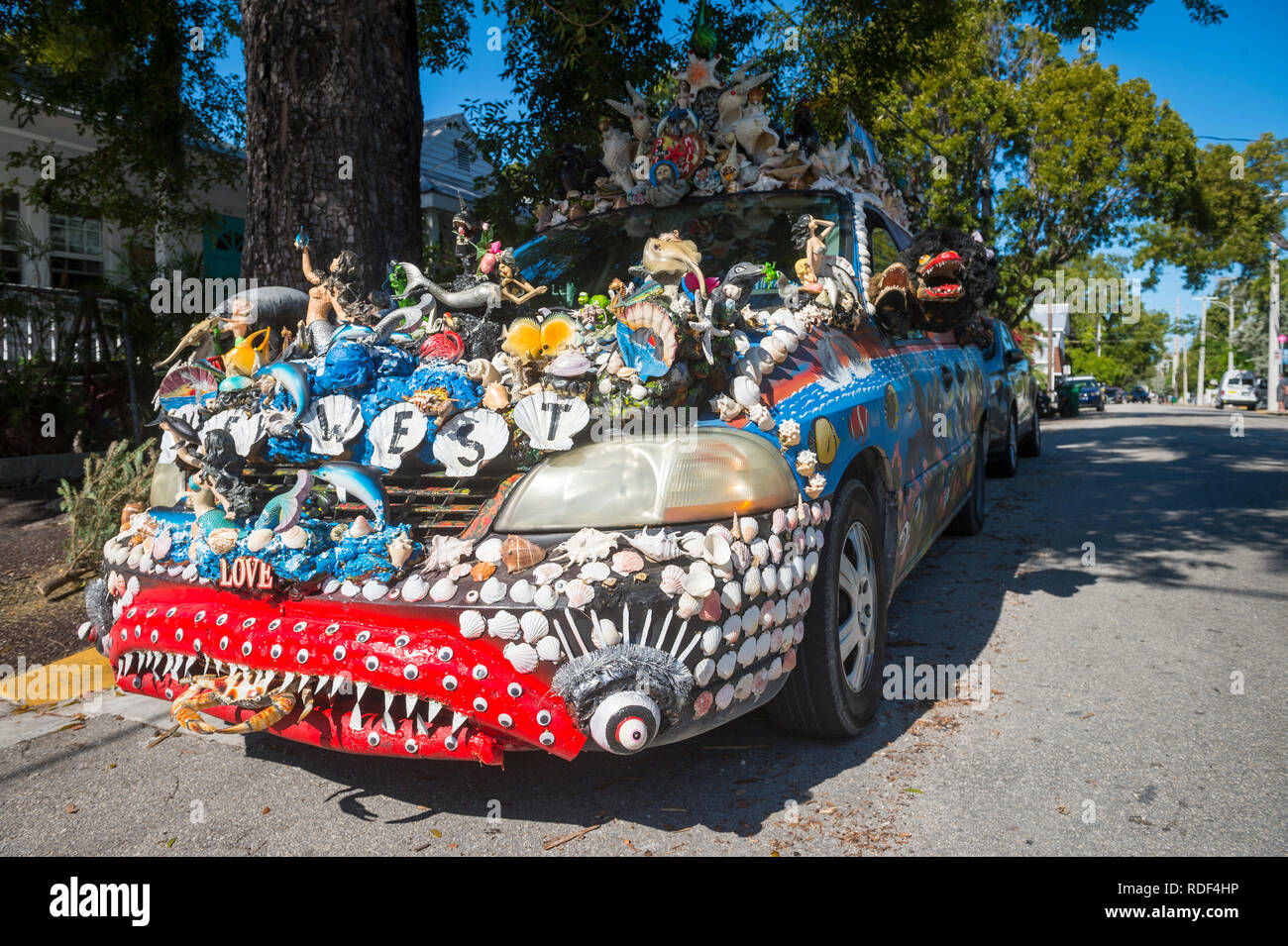 KEY WEST, FLORIDA, USA - JANUARY 14, 2019: A car decorated with a unique mix of shells and figurines stands parked on a quiet residential street. Stock Photo
