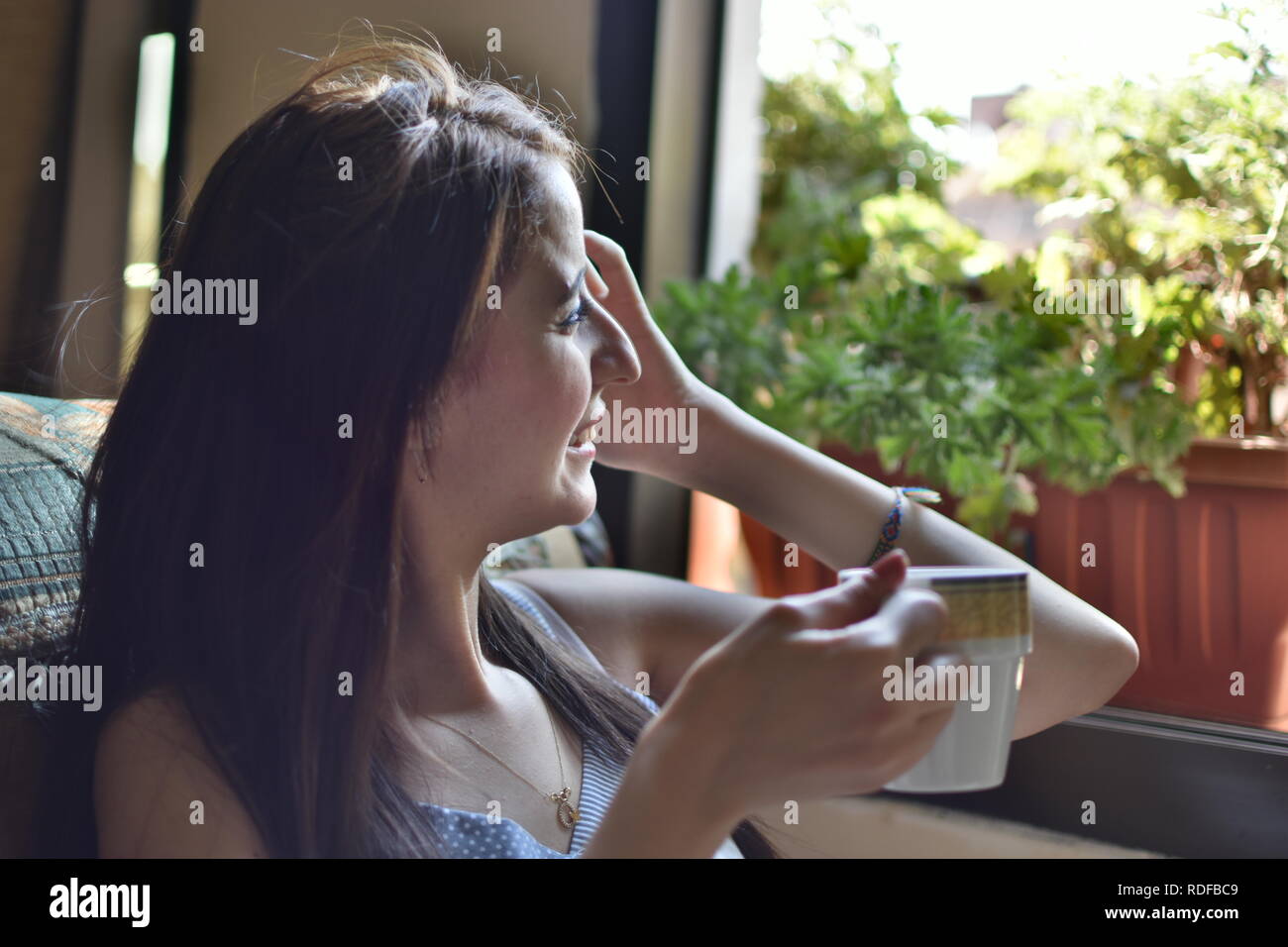 beautiful young woman drinking coffee beside the window Stock Photo