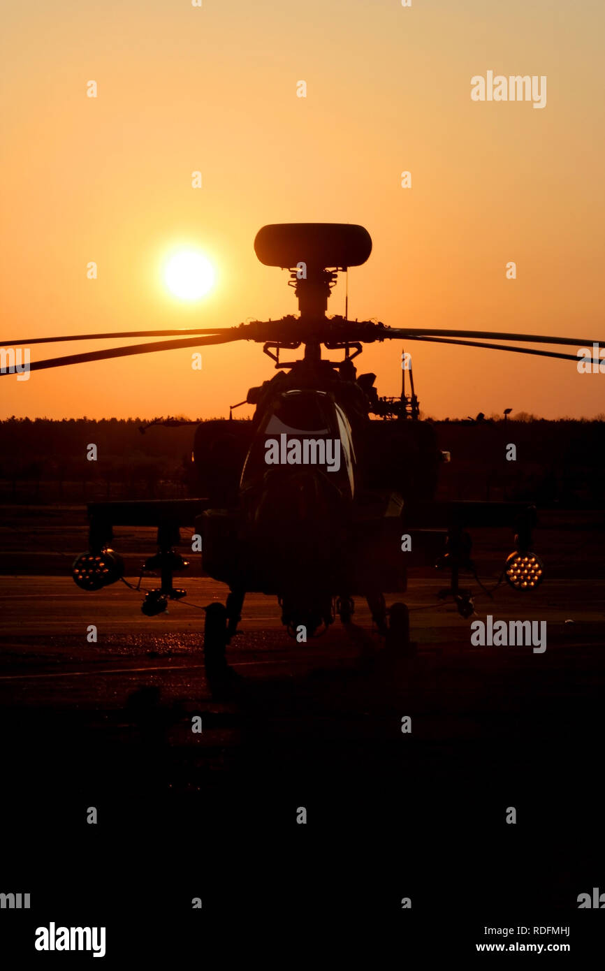 Army Air Corps Apache AH1 attach helicopter silhouetted against the setting sun as it sits at Woodbridge airfield whilst deployed on exercise. Stock Photo