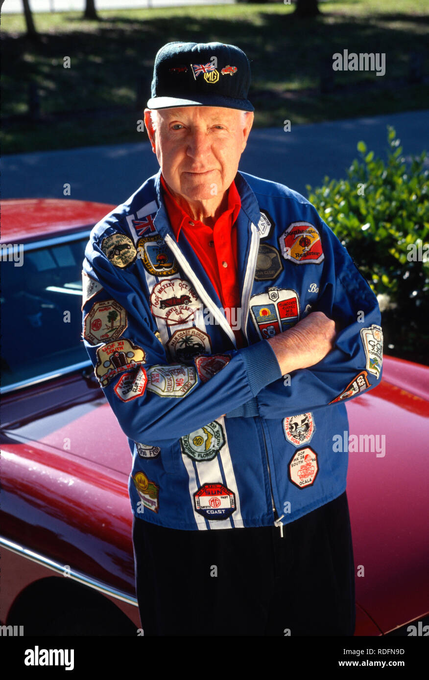Award winning senior car enthusiast poses with his vintage automobile