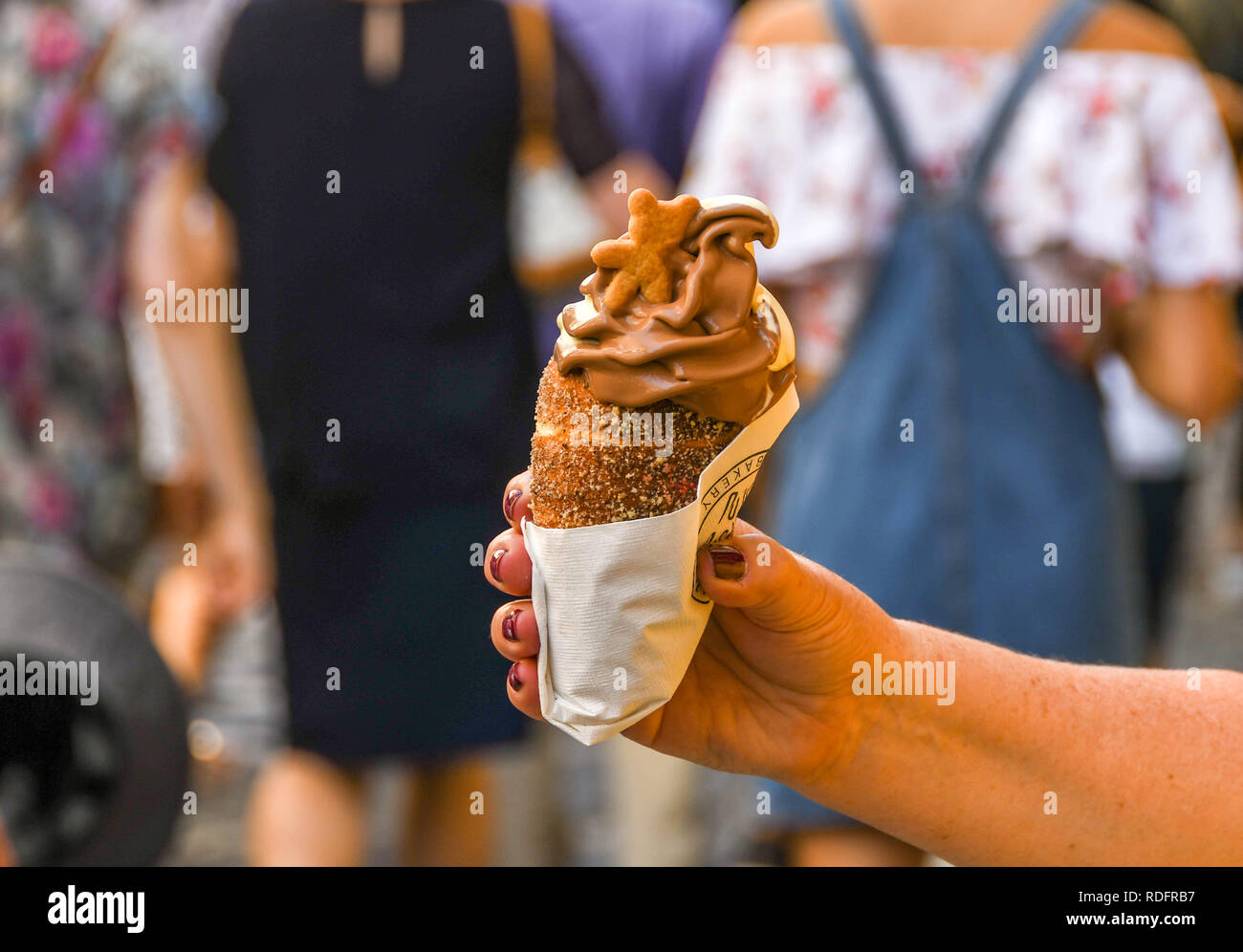 PRAGUE, CZECH REPUBLIC - AUGUST 2018: Person in Prague holding a trdelník chimney, which is a cinnamon pastry filled with soft serve ice cream Stock Photo