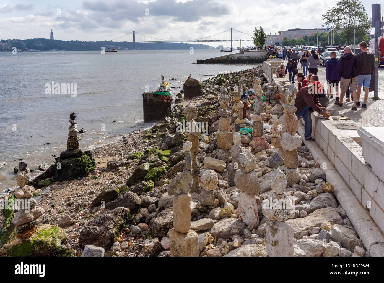 Man stacking stones on the bank of the Tagus River in Lisbon, Portugal Stock Photo