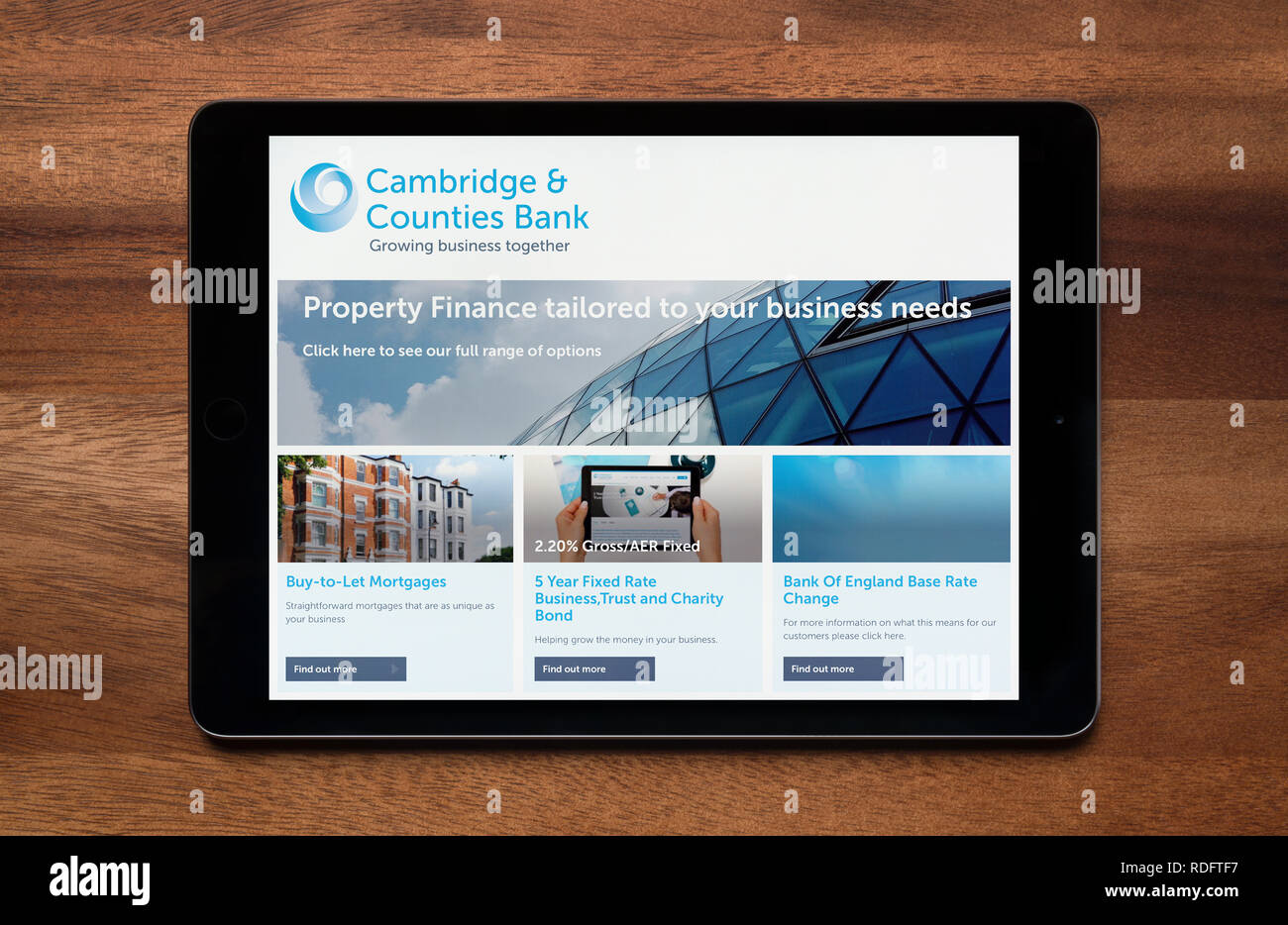 The website of Cambridge and Counties Bank is seen on an iPad tablet, which is resting on a wooden table (Editorial use only). Stock Photo