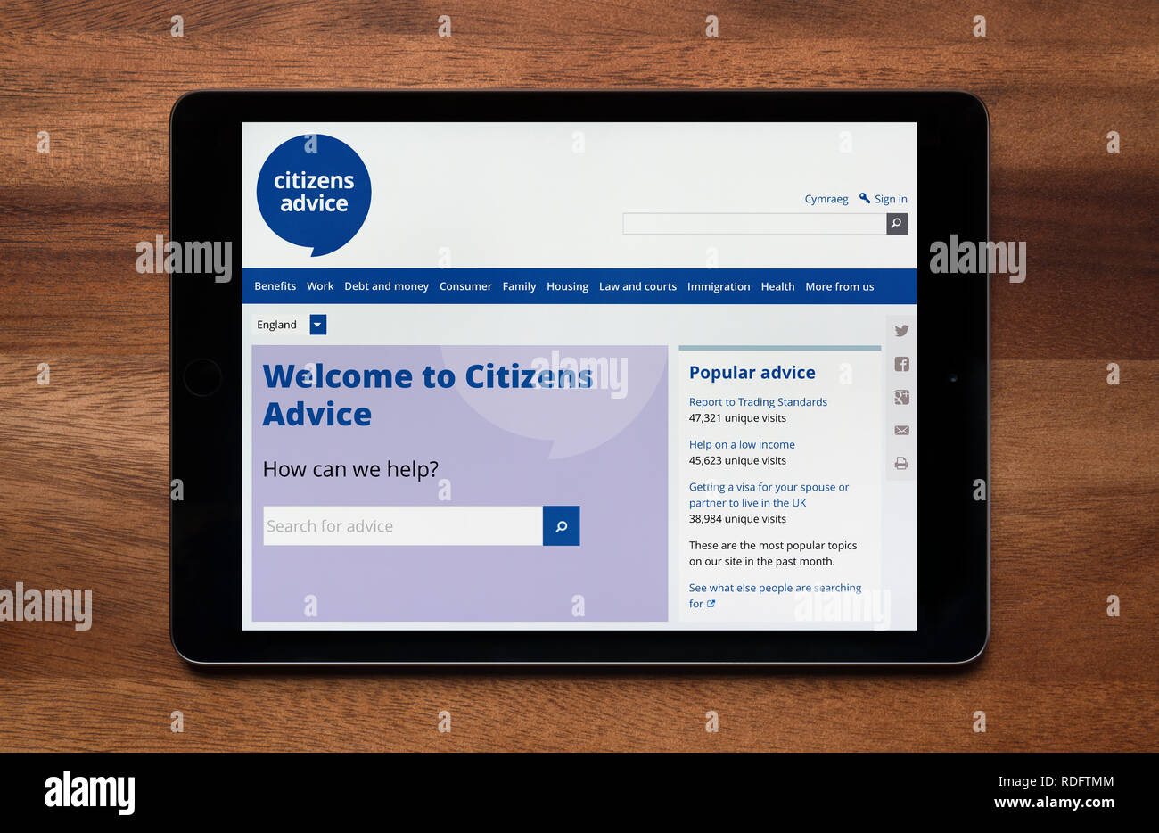 The website of Citizens Advice is seen on an iPad tablet, which is resting on a wooden table (Editorial use only). Stock Photo