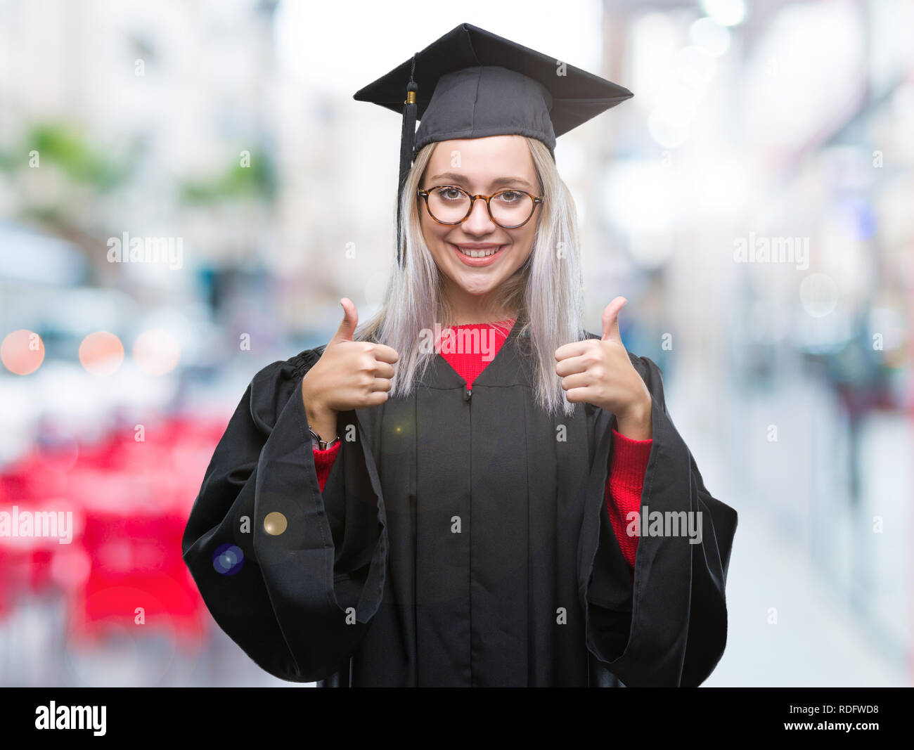 Young blonde woman wearing graduate uniform over isolated background ...