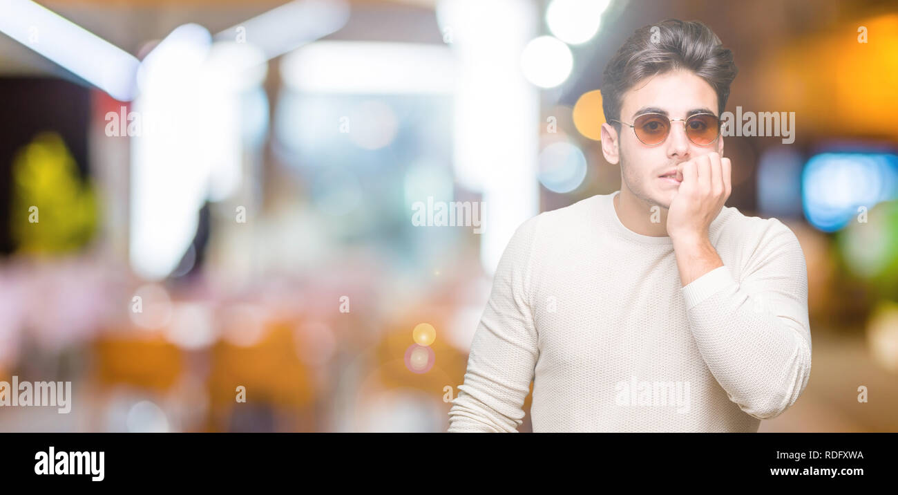 Young handsome man wearing sunglasses over isolated background looking