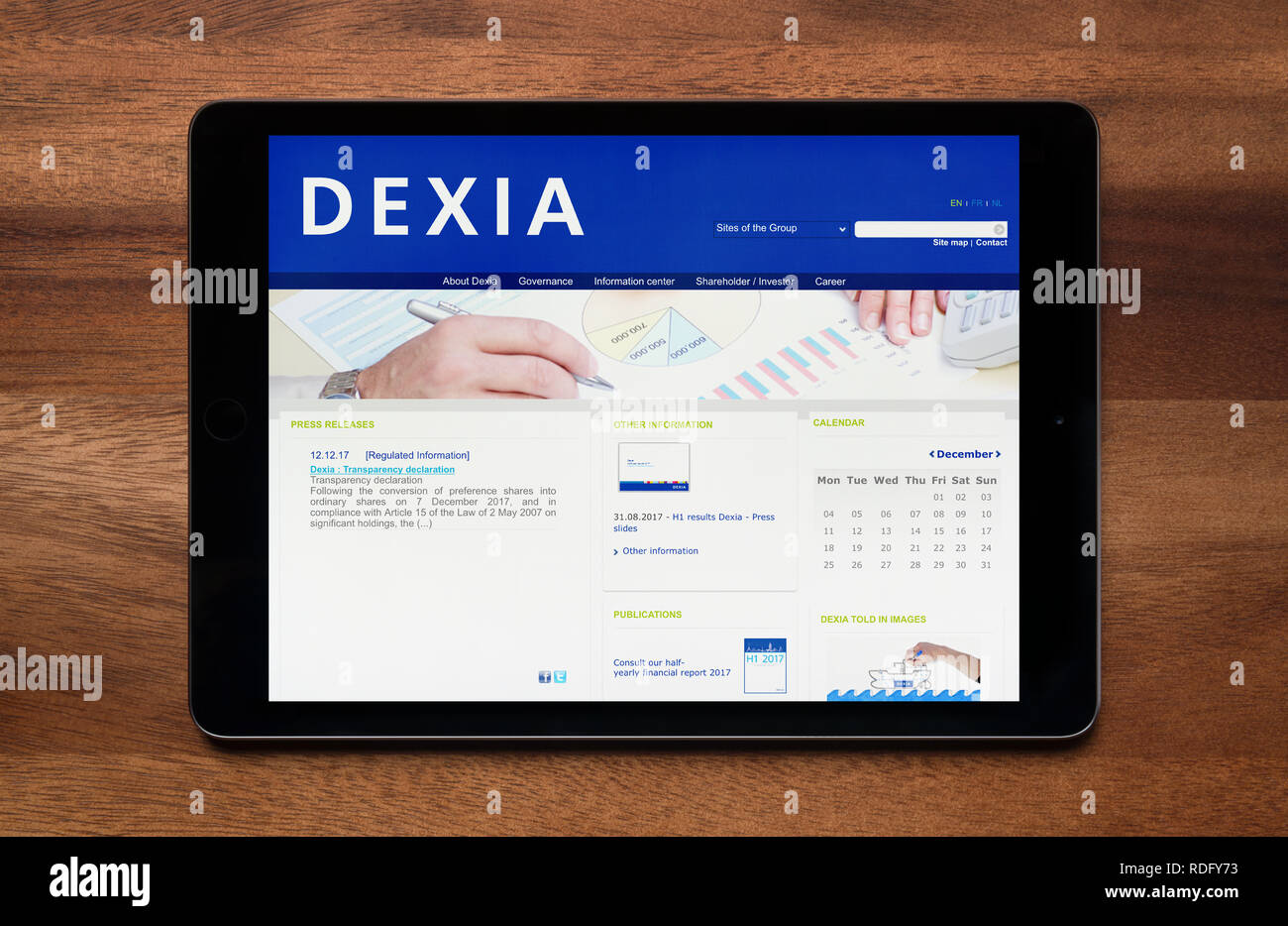 The website of Dexia bank is seen on an iPad tablet, which is resting on a wooden table (Editorial use only). Stock Photo