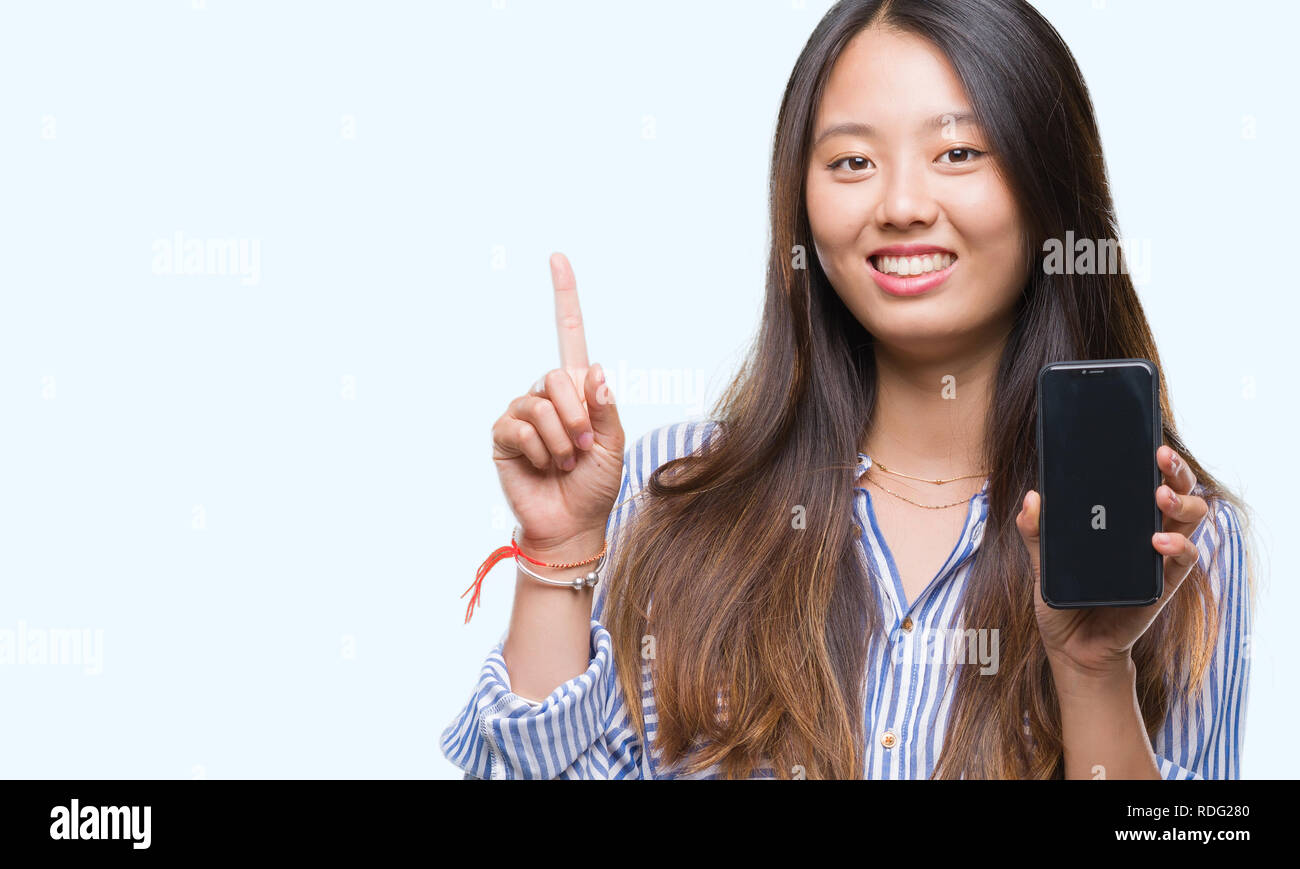 Young asian woman showing blank screen of smartphone over isolated