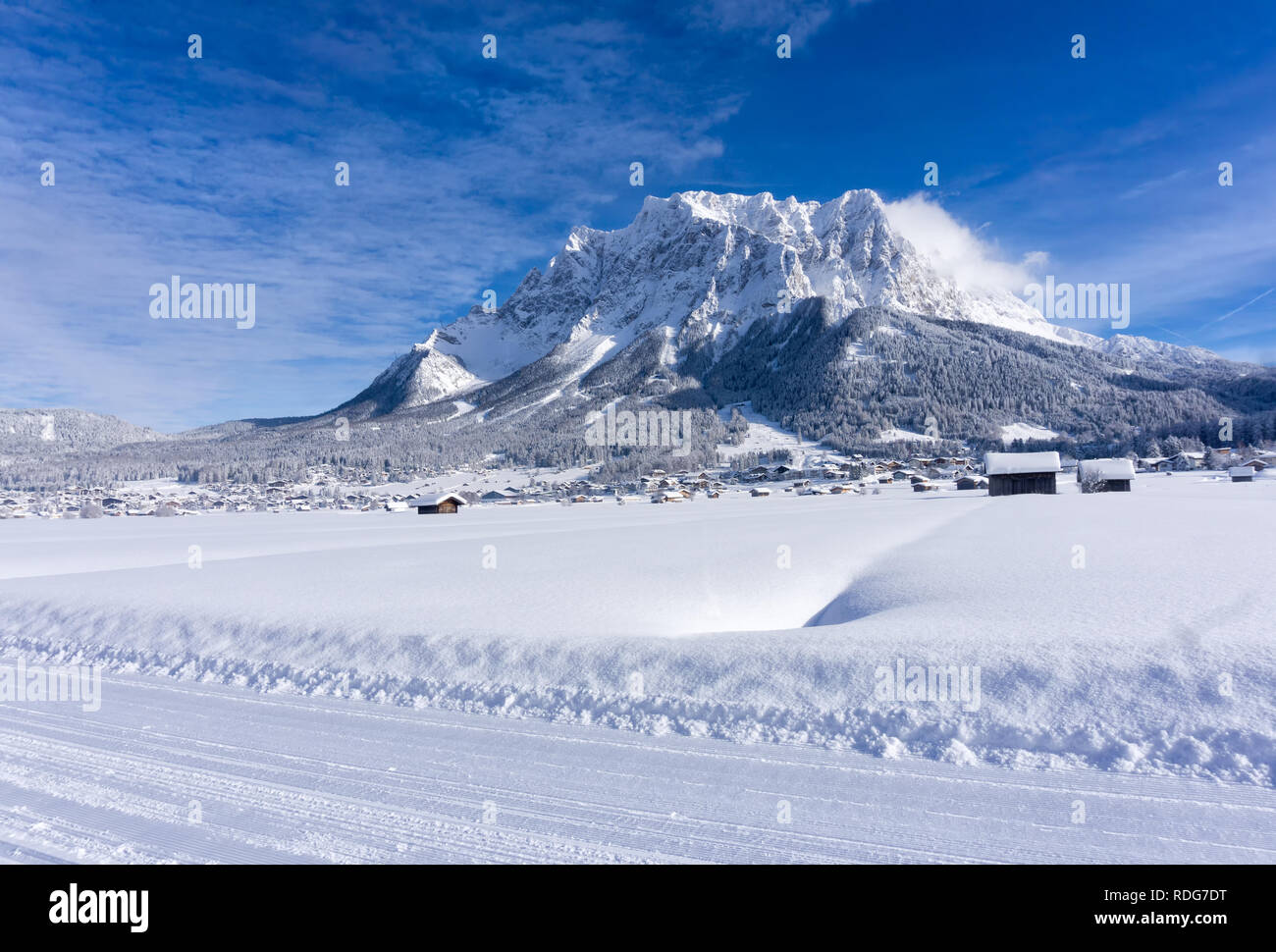 The Zugspitze Massif from the valley of Ehrwald in sunny winter day, groomed ski trails in foreground. Winter mountain landscape. Stock Photo